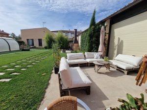 Una zona con sofás en palets en el jardín con vistas a la piscina, zona de relax.