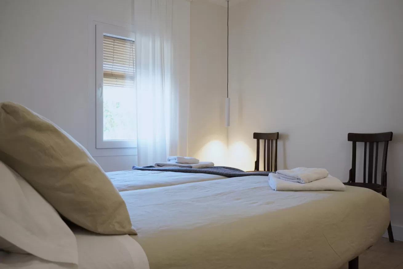 Dormitorio con camas individuales y silla de madera en La Casa del Palomar, casa rural para familias en Vadocondes, Burgos