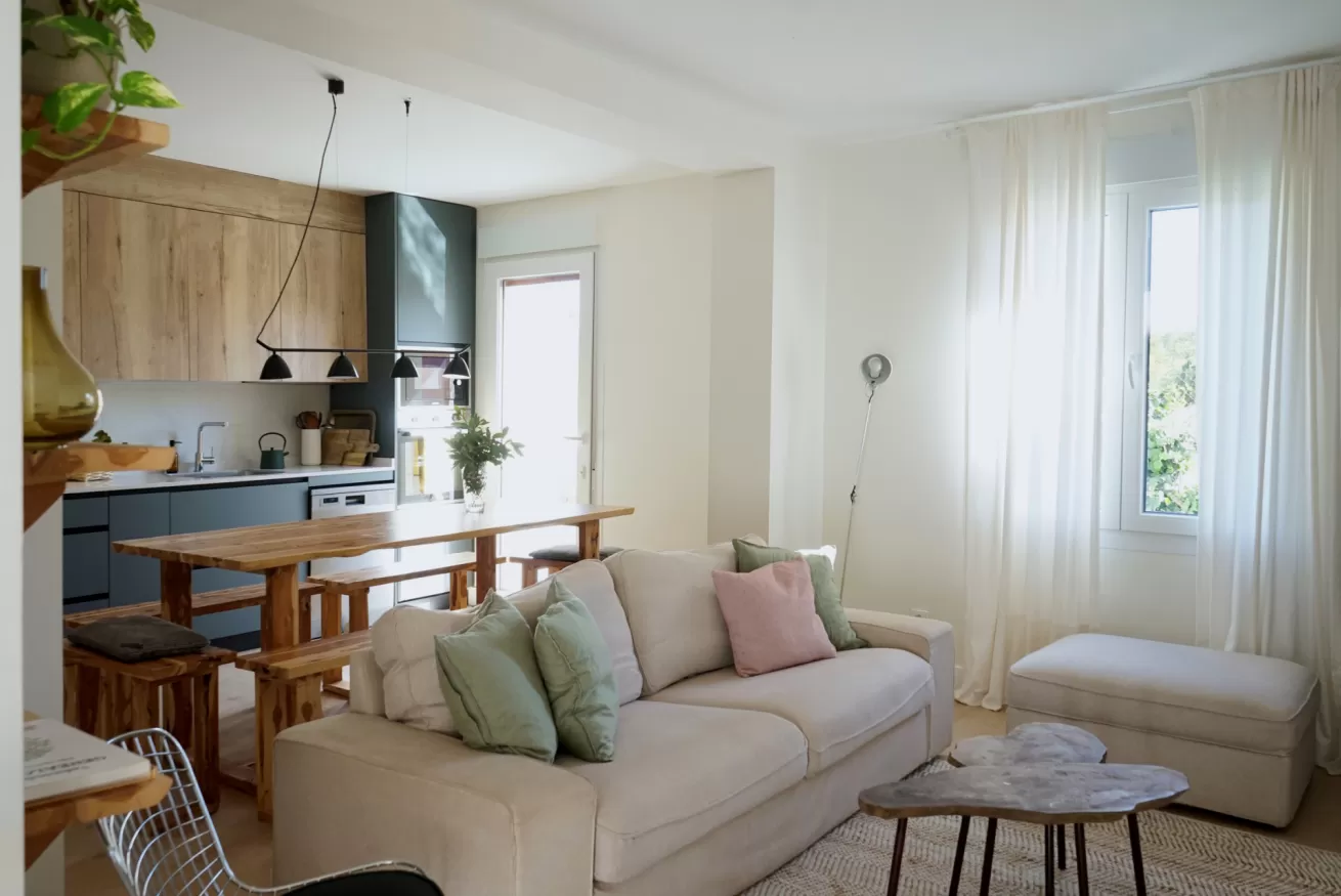 Salón principal de La Casa del Palomar con sofá, mesa y cocina integrada en planta abierta, casa rural orientada al sur en Vadocondes, Burgos